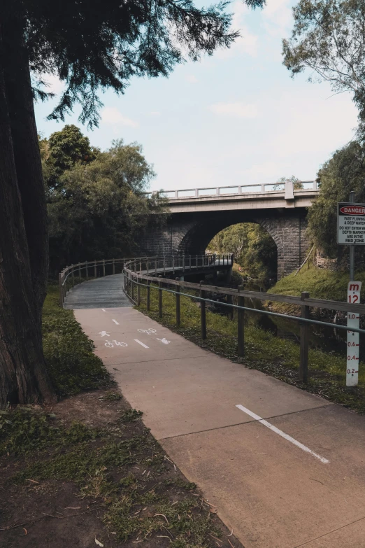 a man riding a bike down a sidewalk next to a bridge, tamborine, tunnels, 🚿🗝📝, no people