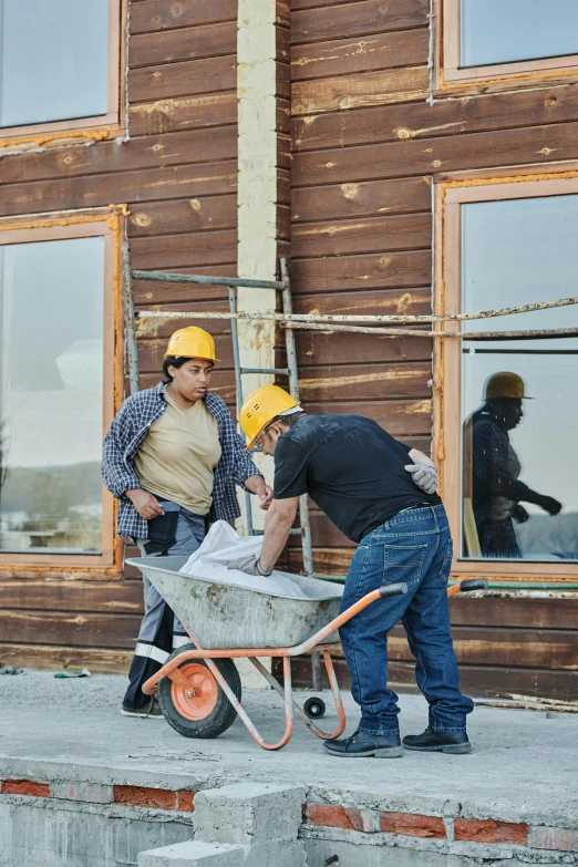 a couple of men standing next to a wheelbarrow, pexels contest winner, arbeitsrat für kunst, gambrel roof building, profile image, wyoming, bright construction materials