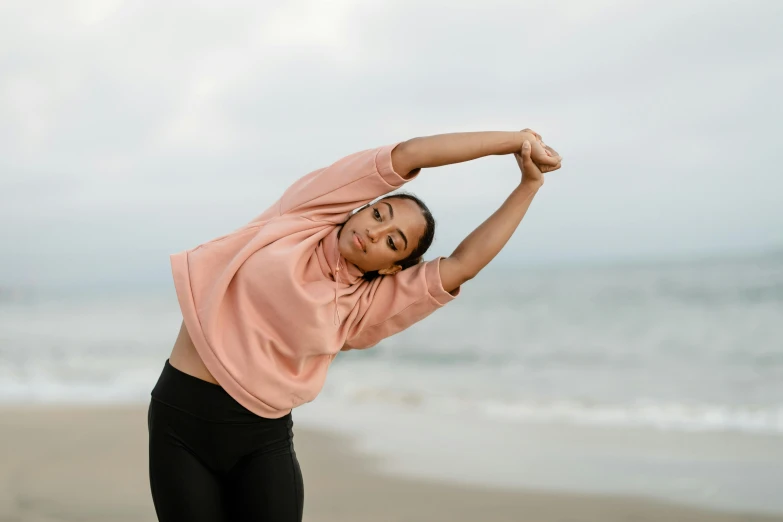 a woman stretching her arms on the beach, pexels contest winner, happening, wearing a track suit, sydney park, african american young woman, plain background