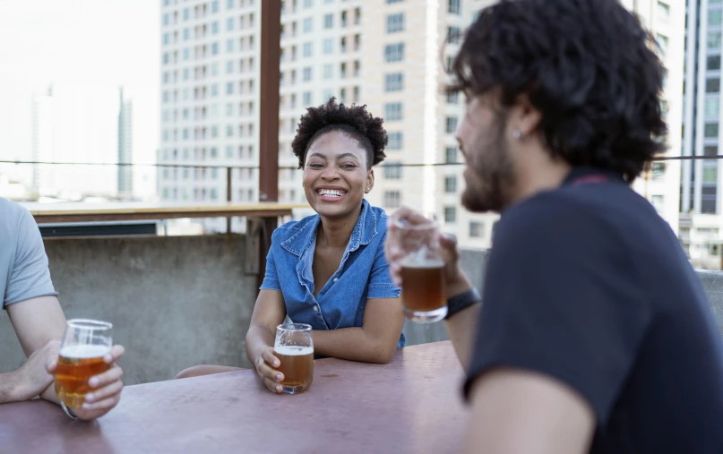 a group of people sitting at a table with beers, by Carey Morris, pexels contest winner, beautiful city black woman only, on rooftop, avatar image, two people