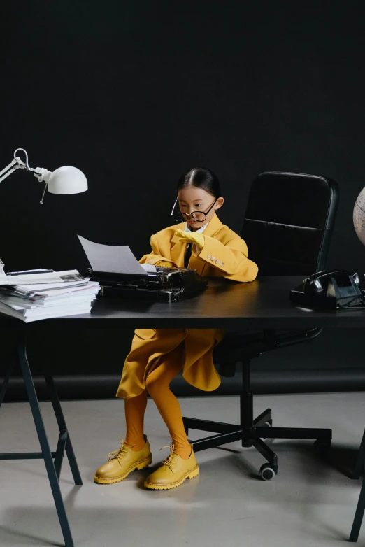 a little girl sitting at a desk with a laptop, by Fei Danxu, pexels contest winner, hypermodernism, black and yellow tracksuit, business clothes, gif, dressed as schoolgirl