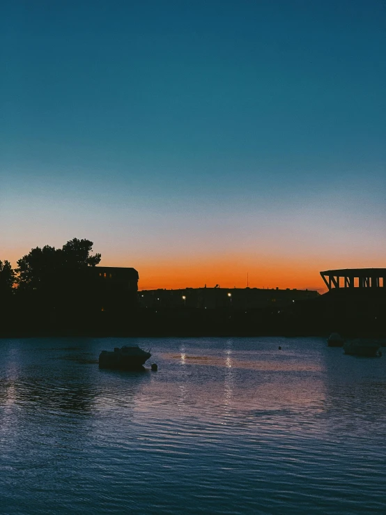 a couple of boats floating on top of a lake, a picture, pexels contest winner, happening, city sunset night, espoo, trending on vsco, low quality photo