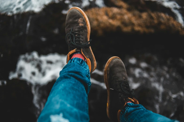 a person standing on top of a rock next to a body of water, pexels contest winner, tight blue jeans and cool shoes, avatar image, lumberjack, gum rubber outsole