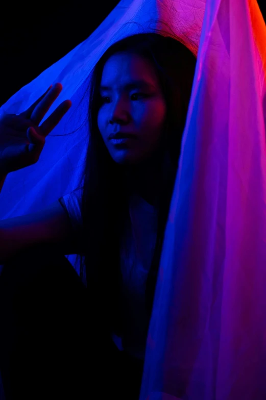 a woman that is standing in the dark, inspired by Ren Hang, unsplash, glowing drapes, at a rave, vietnamese woman, blue and purple lighting