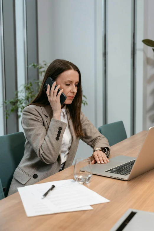a woman sitting at a table talking on a cell phone, laptops, someone lost job, corporate phone app icon, high-quality photo