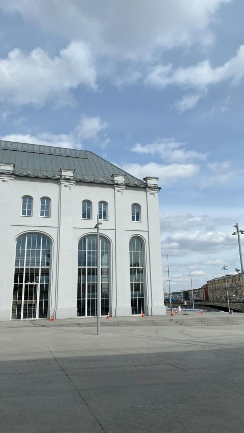 a large white building sitting on the side of a road, inspired by Tilo Baumgärtel, train station, tall windows, jörmungandr, view from front