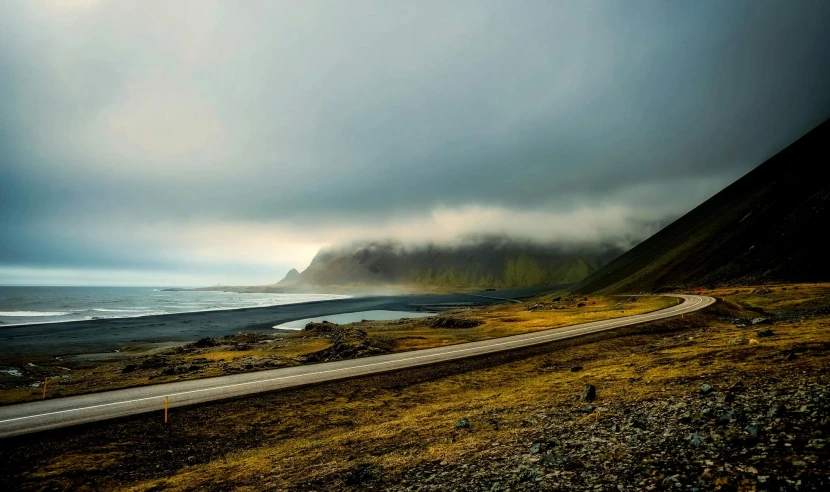 a car driving down a road next to a body of water, by Hallsteinn Sigurðsson, pexels contest winner, green smoggy sky, windy beach, devils horns, conde nast traveler photo