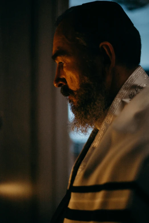 a man standing in front of a window with a lit candle, arab man light beard, 2 0 2 1 cinematic 4 k framegrab, in profile, ( ( theatrical ) )