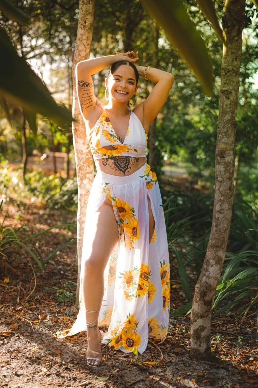 a woman standing next to a tree with sunflowers on it, bralette, white sarong, alanis guillen, body covered in floral tattoos