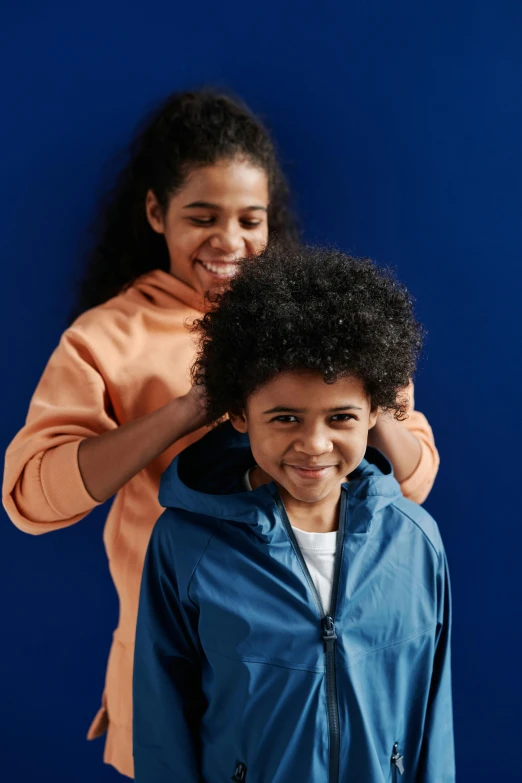 a couple of women standing next to each other, wearing a blue hoodie, for junior, curls on top, zoomed in