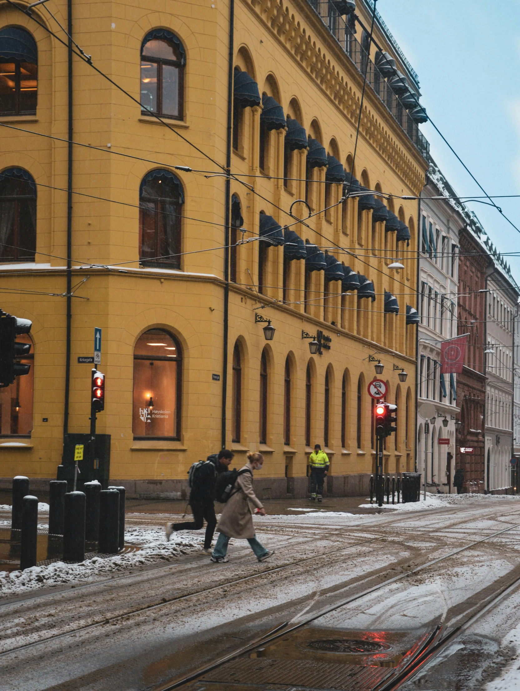 a couple of people walking across a snow covered street, by Christen Dalsgaard, pexels contest winner, old building, 🚿🗝📝