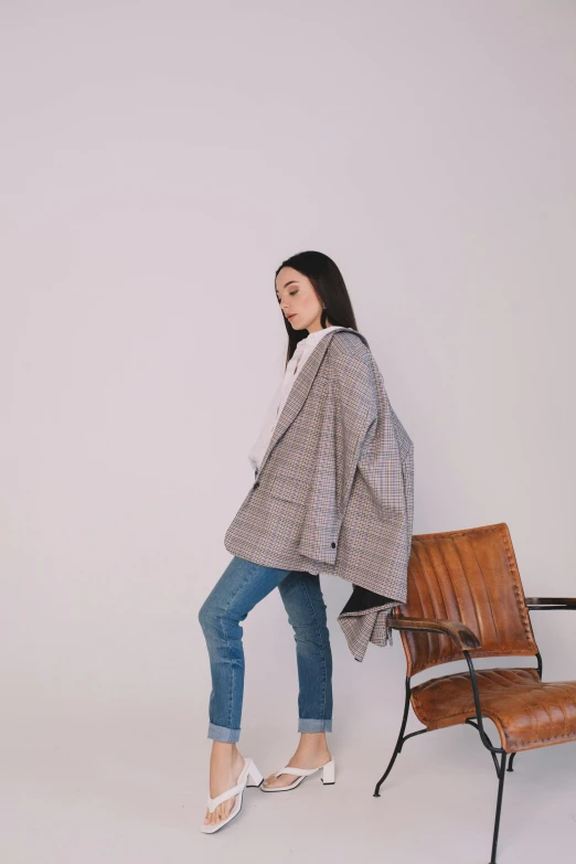 a woman standing next to a chair in a room, by Simon Gaon, unsplash, tartan hoodie, korean women's fashion model, grey jacket, product introduction photo