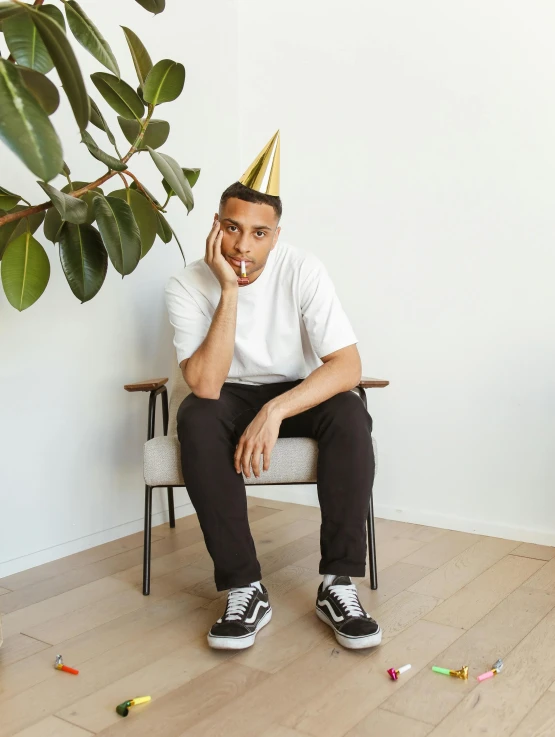 a man in a party hat sitting on a chair, inspired by Ryan Yee, happening, posing for a picture, riyahd cassiem, profile image, plain background