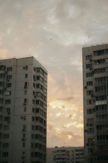 a couple of tall buildings sitting next to each other, inspired by Elsa Bleda, soviet town, low quality photo, sky setting, medium-shot