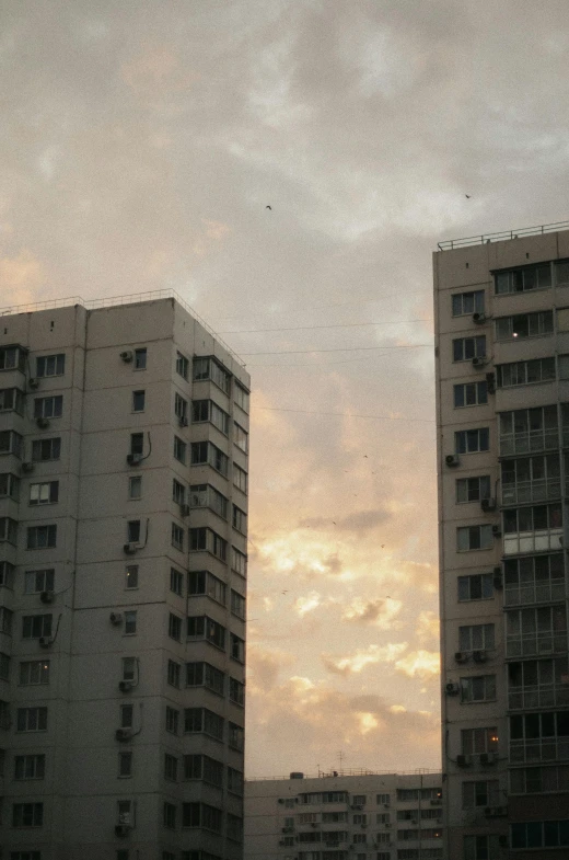 a couple of tall buildings sitting next to each other, inspired by Elsa Bleda, soviet town, low quality photo, sky setting, medium-shot