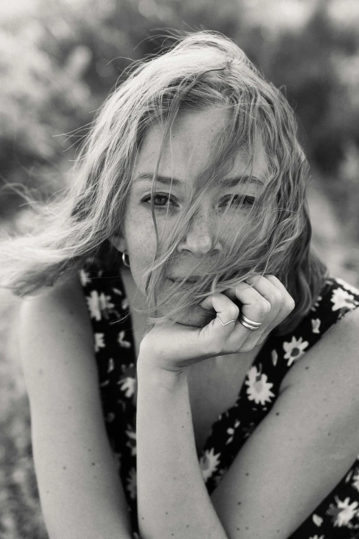 a black and white photo of a woman sitting in a field, unsplash, photorealism, sydney sweeney, wet skin and windblown hair, icon, press photos