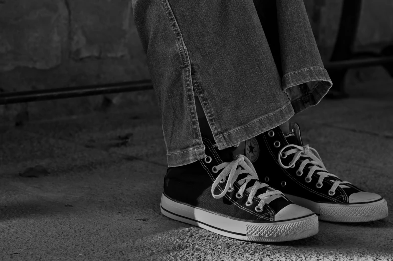 a black and white photo of a person sitting on a skateboard, a black and white photo, pexels, sots art, blue jeans and grey sneakers, converse, sitting on a store shelf, close up high detailed