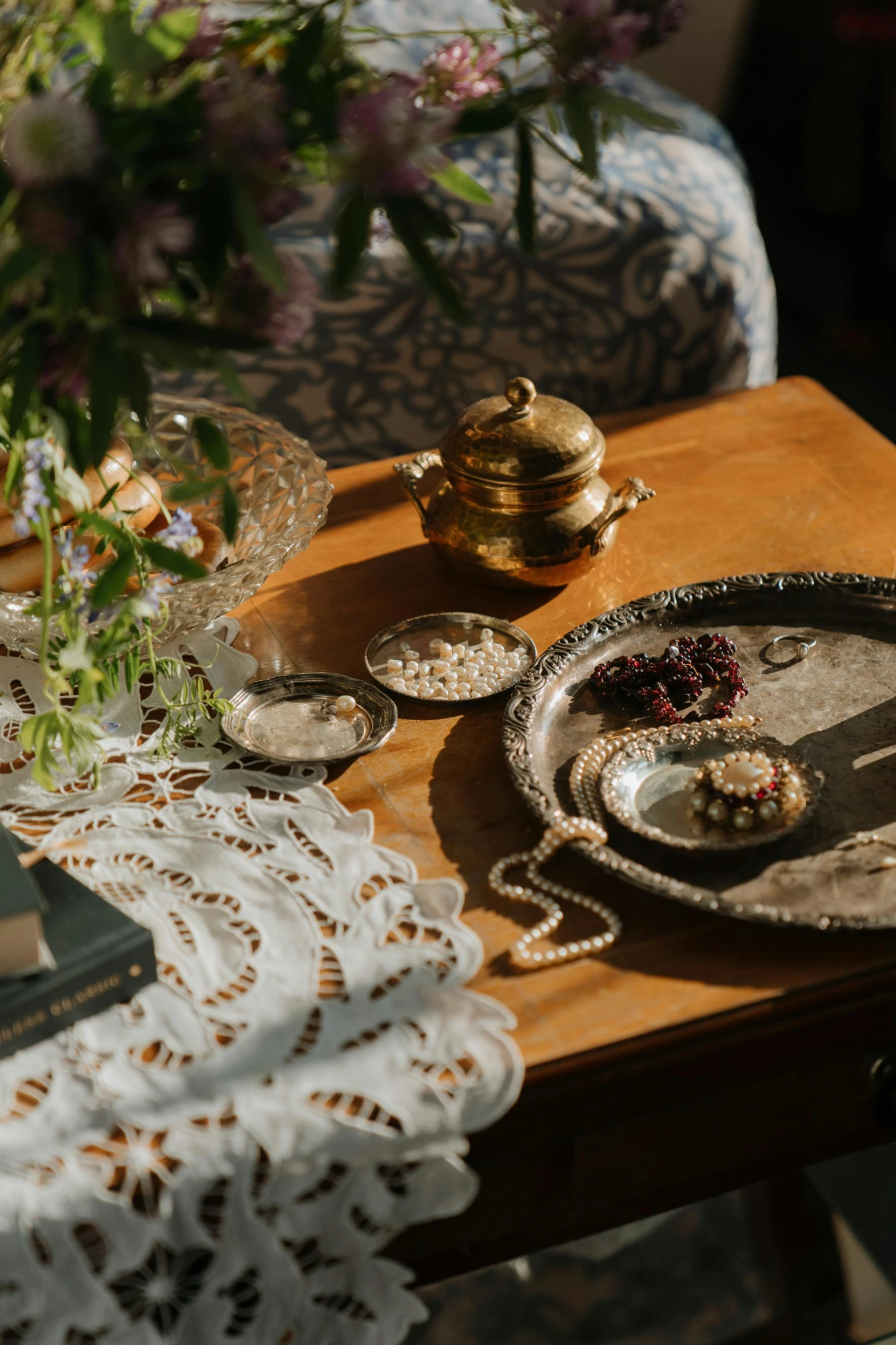 a wooden table topped with a book next to a vase of flowers, inspired by Károly Markó the Elder, unsplash, baroque, silver platter, 1900's, middle eastern details, holy ceremony