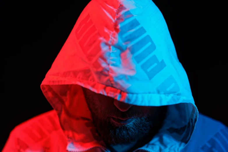 a close up of a person wearing a hoodie, by Adam Marczyński, unsplash, hyperrealism, red and blue neon, wearing jacket, wearing translucent sheet, advertising photo