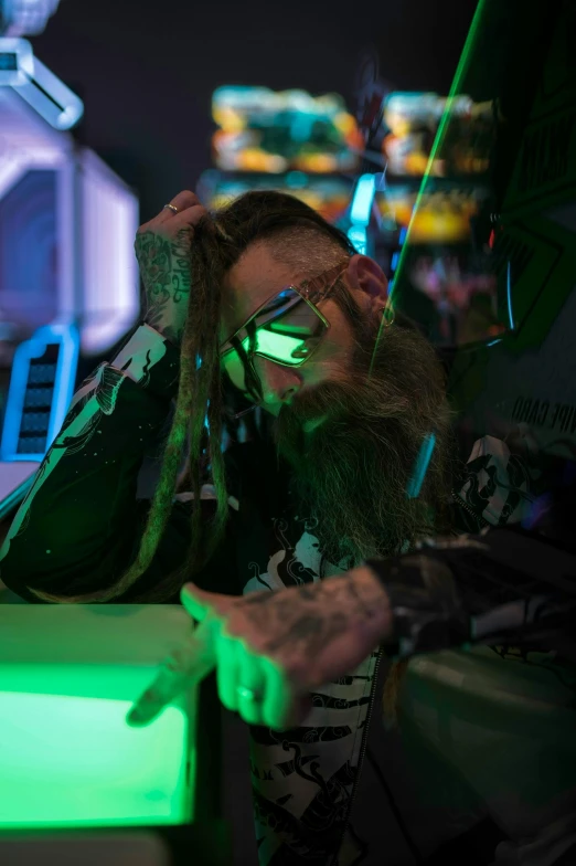 a man sitting in front of a laptop computer, cyberpunk art, featured on reddit, long glowing hair, tattoo parlor photo, cyberpunk sunglasses, standing in a starbase bar