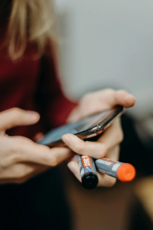 a close up of a person holding a cell phone, a picture, markers, grey orange, steroid use, checking her phone