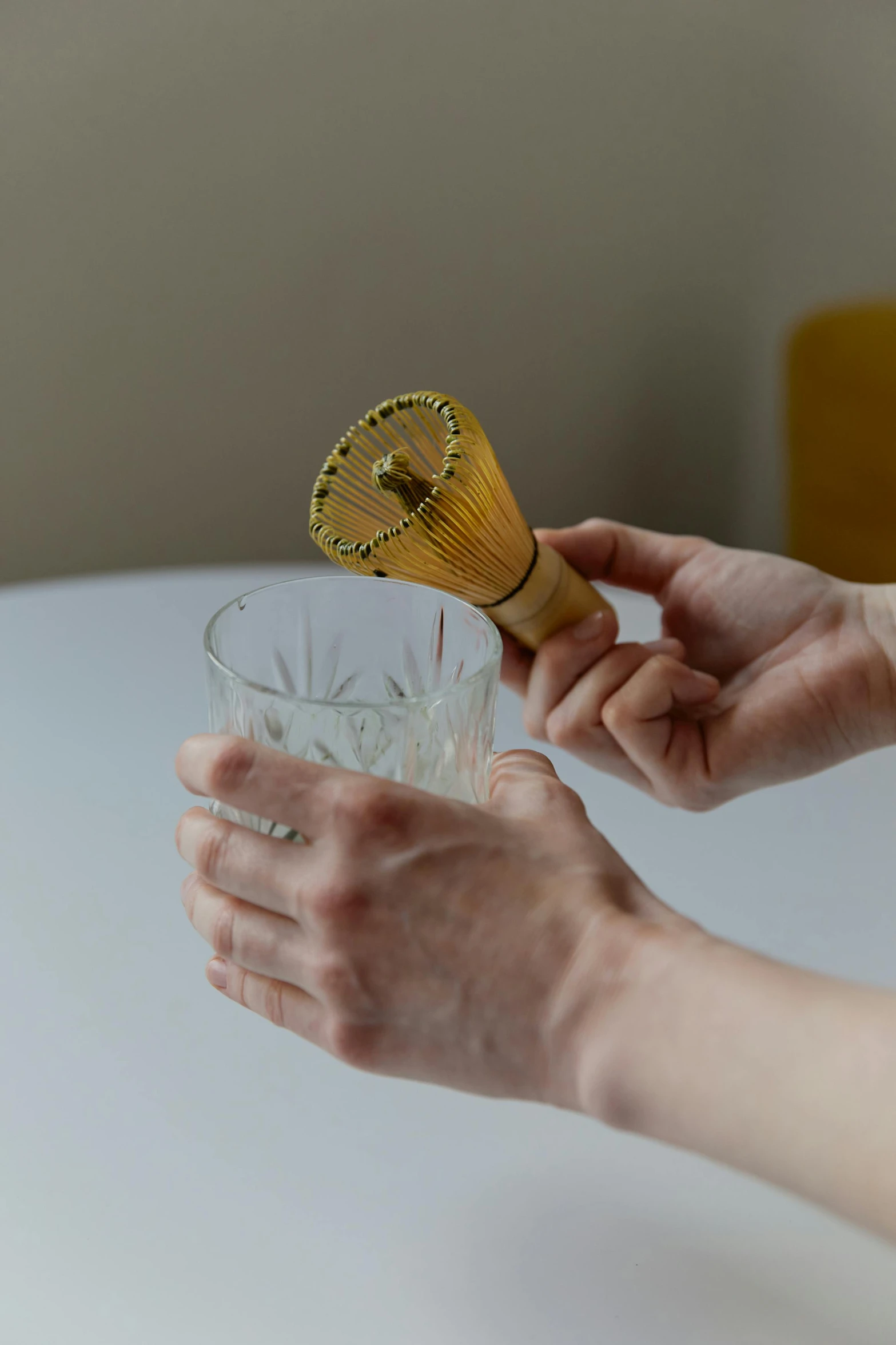 a person holding a whisk over a glass of water, inspired by Kanō Shōsenin, unsplash, art nouveau, “ golden cup, product display photograph, made of bamboo, assembly instructions