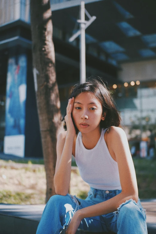 a woman sitting on a curb talking on a cell phone, by Tan Ting-pho, pexels contest winner, realism, wearing a cropped top, set on singaporean aesthetic, woman's face looking off camera, sunfaded