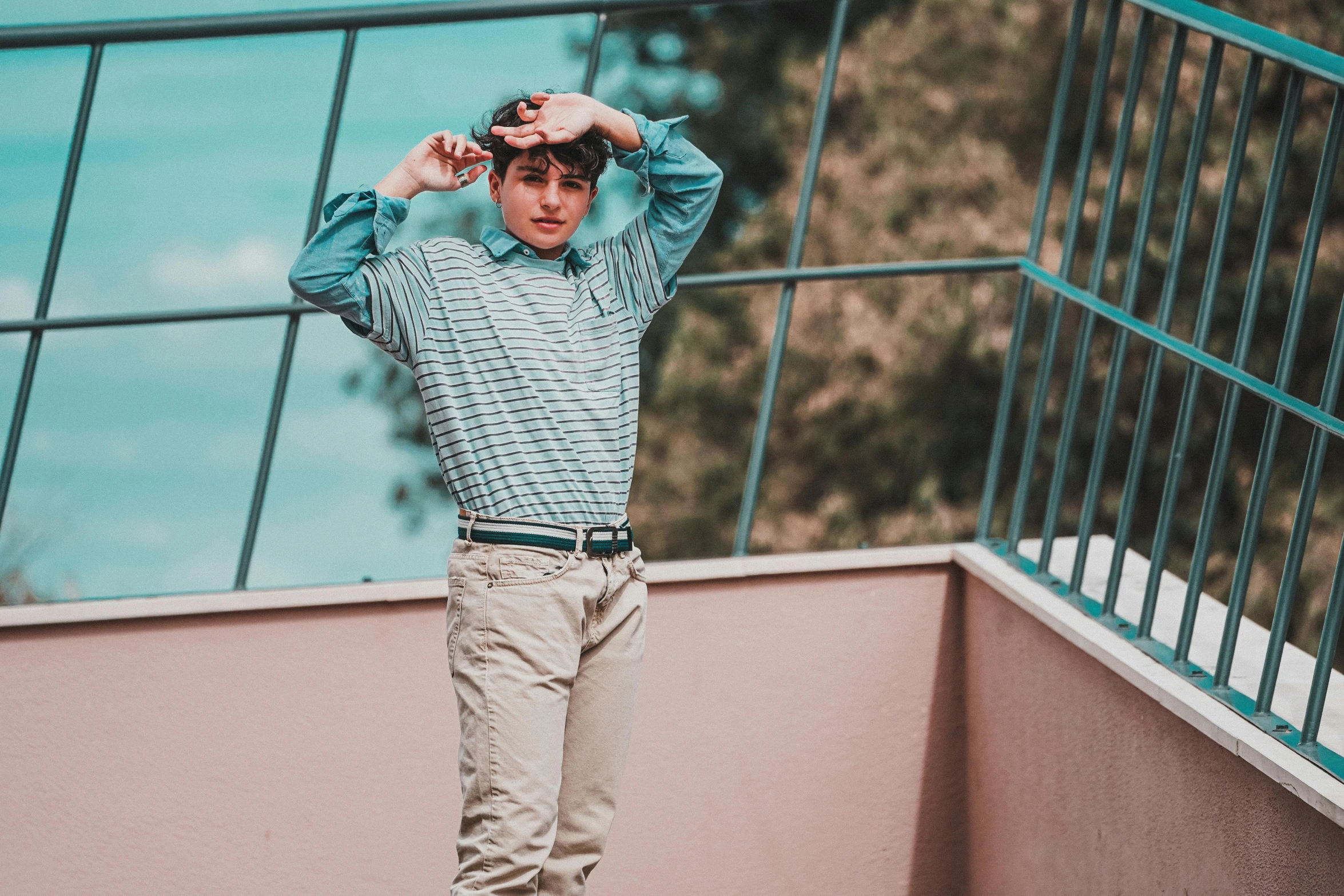 a young man standing on top of a skateboard, a colorized photo, inspired by Elsa Bleda, pexels contest winner, wearing stripe shirt, ((greenish blue tones)), delicate androgynous prince, thinking pose