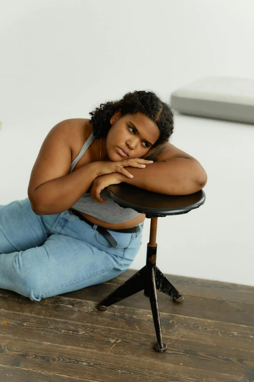 a woman sitting on top of a wooden floor, inspired by Esaias Boursse, trending on pexels, photorealism, an overweight, imaan hammam, sitting on a stool, concerned