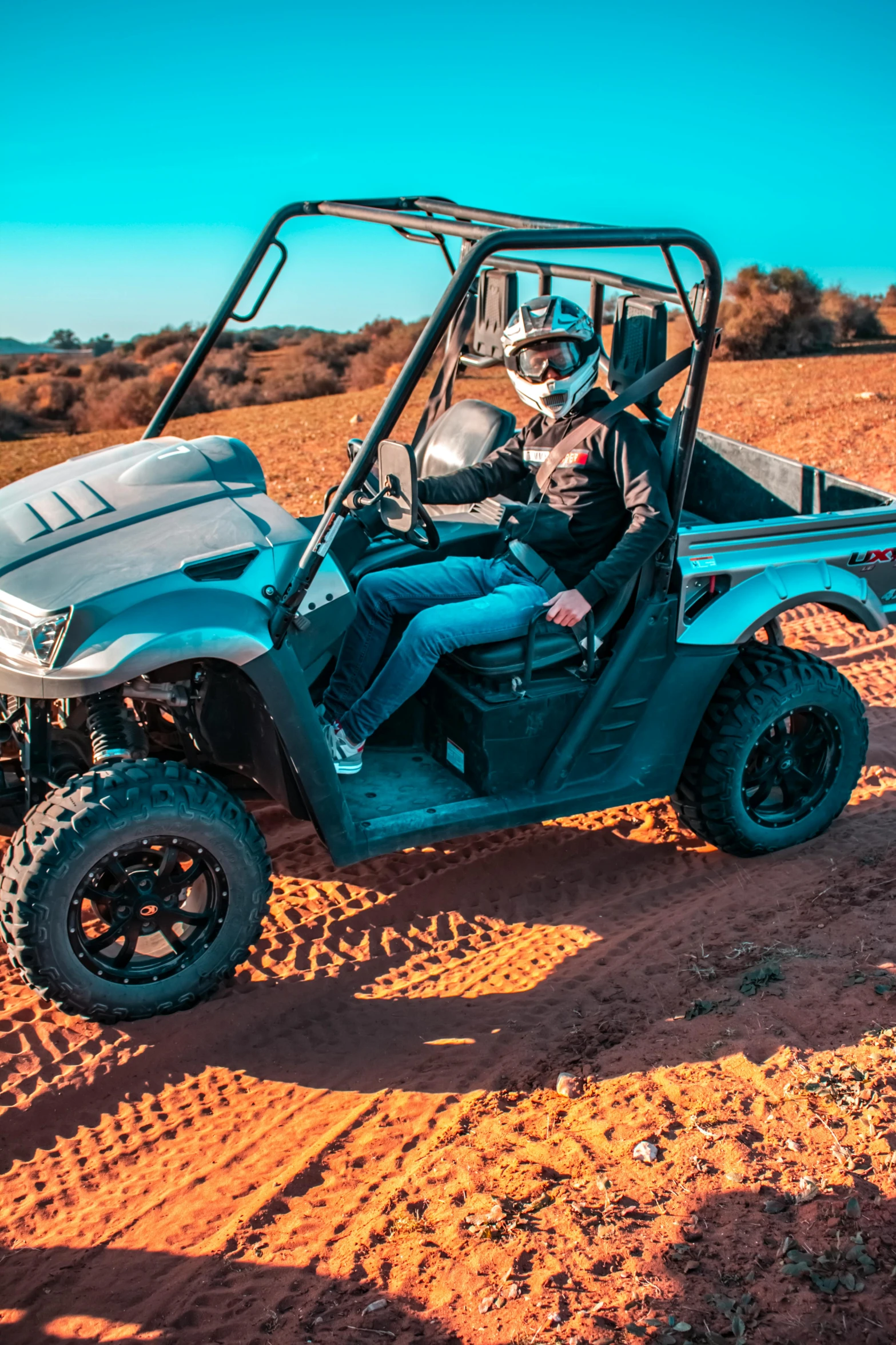 a man driving a utto on a dirt road, steel gray body, desert mirage, sitting down, action sports