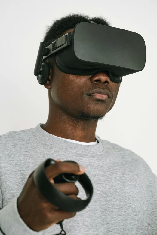 a man in a gray shirt holding a video game controller, afrofuturism, wearing a vr headset, 2019 trending photo, press shot, floating headsets