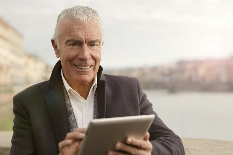 a close up of a person holding a tablet, by John Murdoch, mature male, at the waterside, looking smart, white-haired