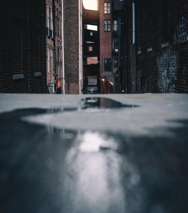 a puddle of water in the middle of a city street, pexels contest winner, graffiti, moody evening light, [[empty warehouse]] background, shady alleys, today\'s featured photograph 4k