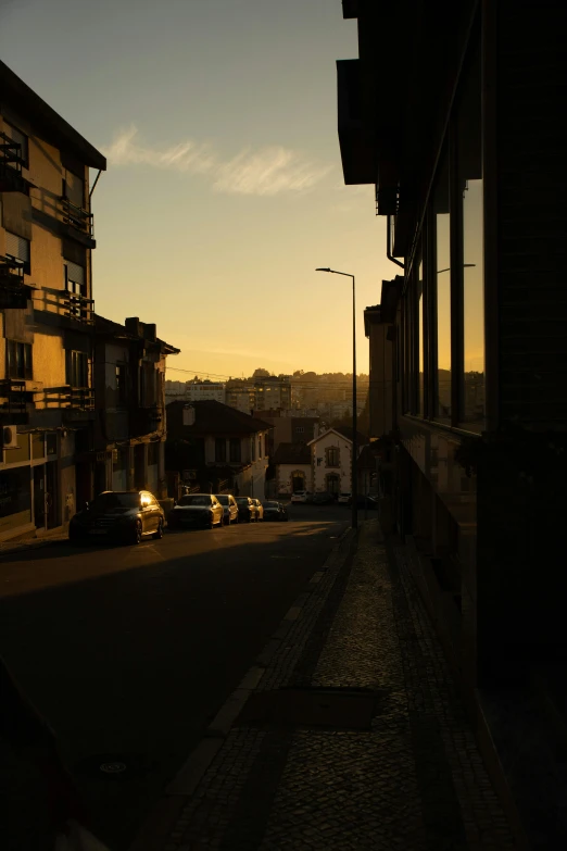 a street with cars parked on the side of it, by Tamas Galambos, ((sunset)), gui guimaraes, top of the hill, morning light