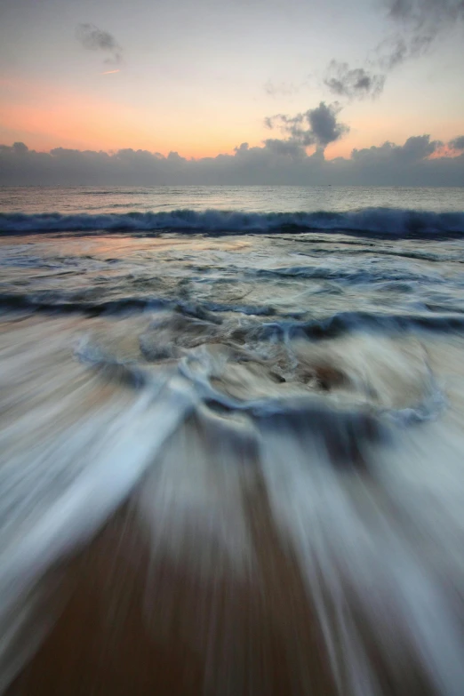 a large body of water sitting on top of a sandy beach, by Daniel Seghers, massive motion blur, dawn, oceans, splash image