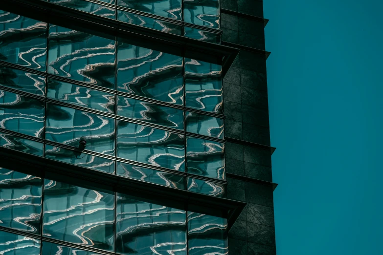 a tall building with a blue sky in the background, inspired by Elsa Bleda, pexels contest winner, modernism, black and teal paper, liquid glass, reflecting light, thumbnail