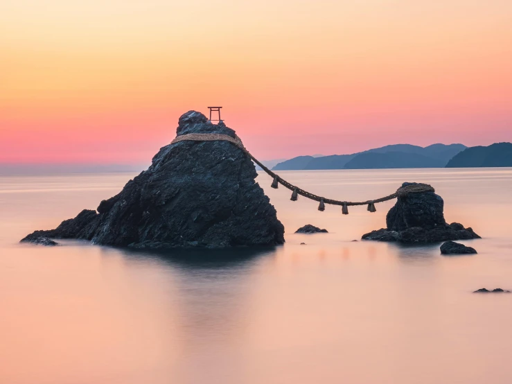 a lighthouse sitting on top of a rock in the ocean, by Torii Kiyomoto, unsplash contest winner, sōsaku hanga, rope bridge, pink zen style, stone bridge, sunset kanagawa prefecture