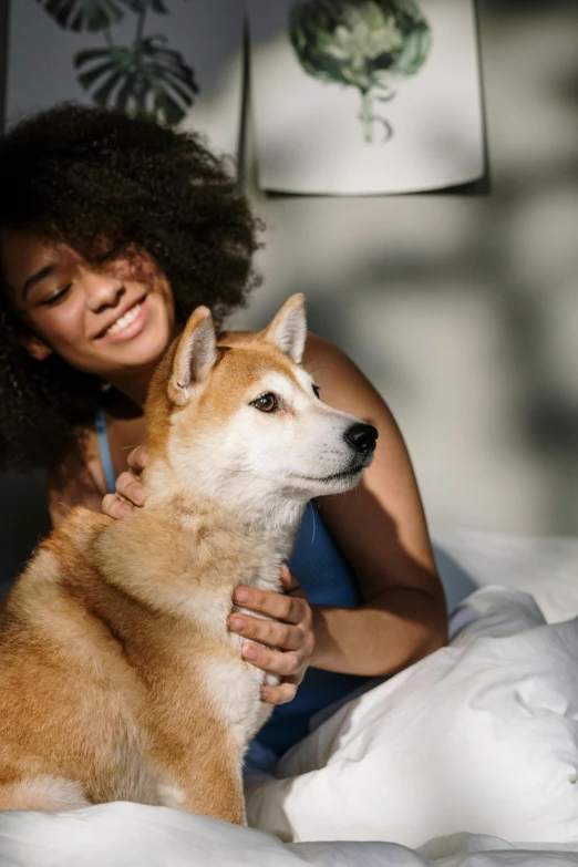 a woman sitting on a bed with a dog, a stock photo, trending on unsplash, renaissance, shiba inu, hugging, photo of a black woman, multiple stories