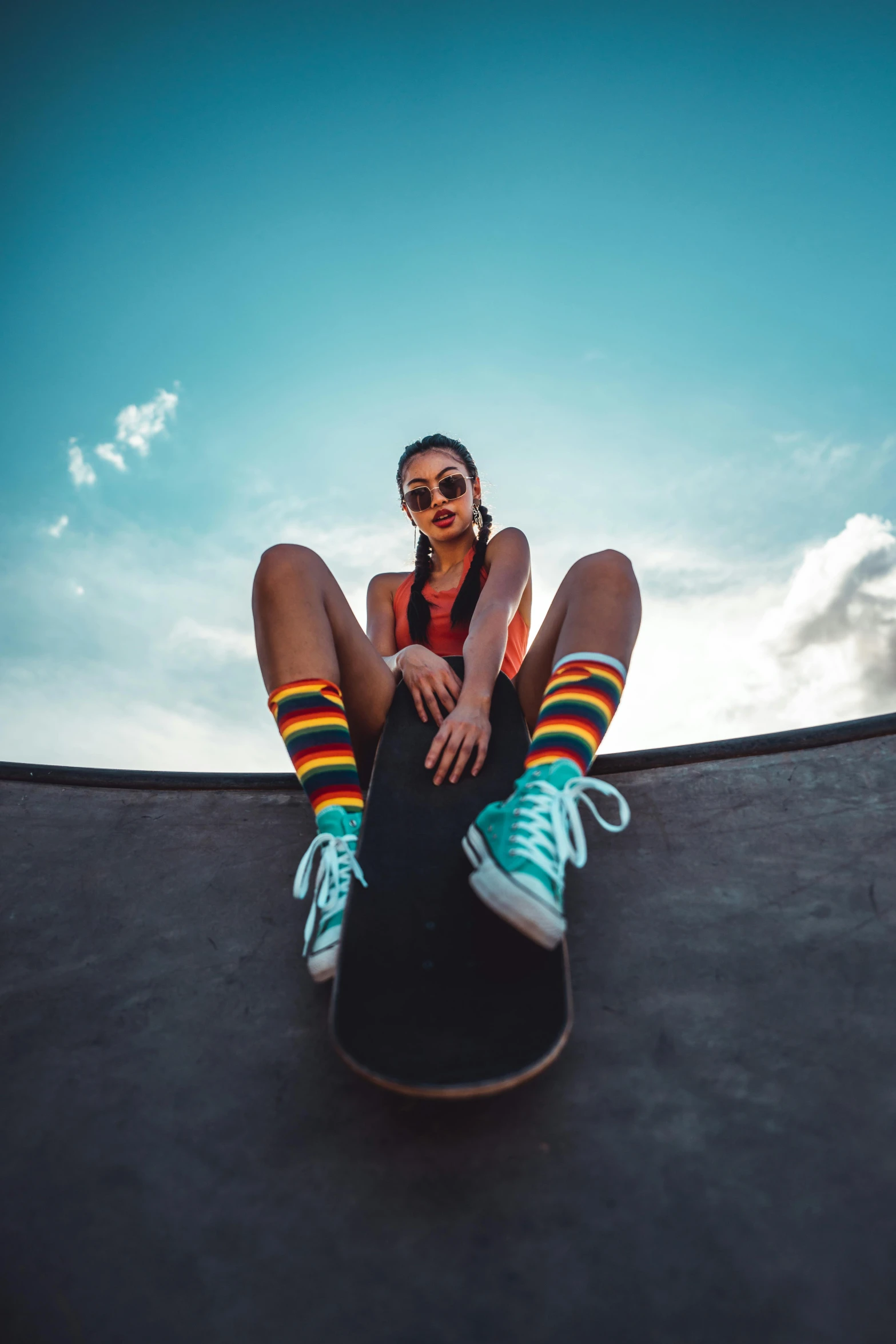 a woman sitting on top of a skateboard on a ramp, trending on pexels, colorful outfit, gopro photo, striped socks, wearing shades