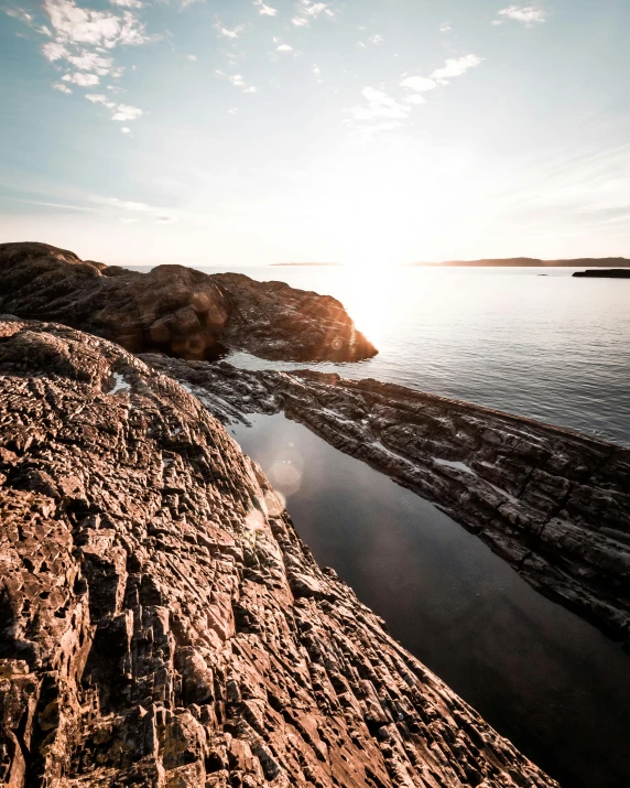 a large body of water sitting on top of a rocky shore, by Jesper Knudsen, pexels contest winner, copper veins, archipelago, late afternoon sun, pov photo