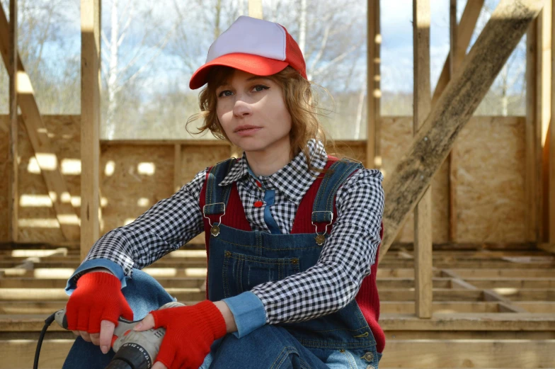 a woman sitting on top of a hard wood floor, inspired by Mario Cooper, pexels, photorealism, wearing plumber uniform, on a farm, cosplay photo, red cap