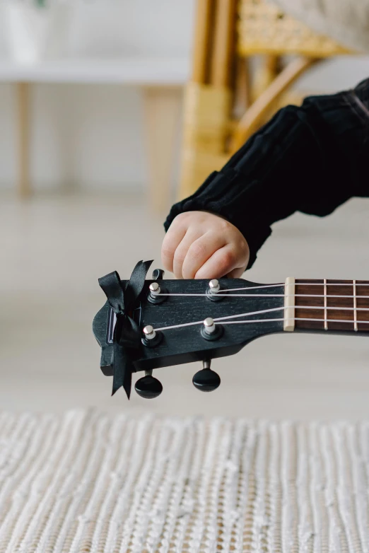 a close up of a person playing a guitar, toys, black bow tie, toddler, epk