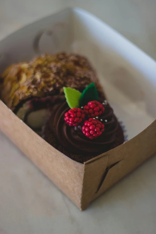 a close up of a pastry in a box on a table, by Jessie Algie, pexels, diecut, raspberry, chocolate frosting, cornucopia