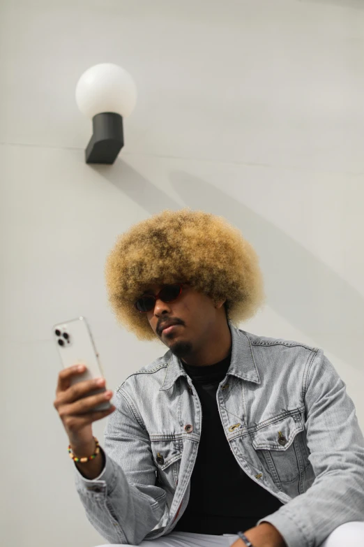 a man that is sitting down with a cell phone, an album cover, trending on pexels, funk art, short blonde afro, mirror selfie, headshot profile picture, flax