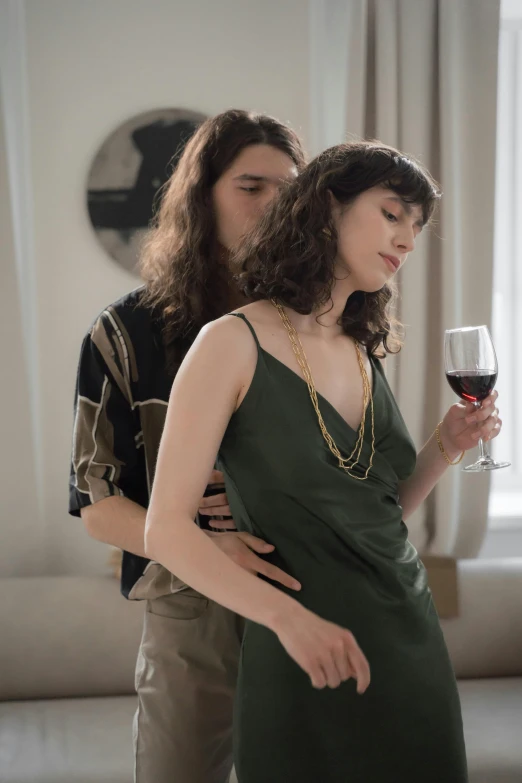 a man standing next to a woman holding a glass of wine, a portrait, inspired by Nan Goldin, trending on pexels, renaissance, brunette woman, ( ( theatrical ) ), stoya, tight around neck