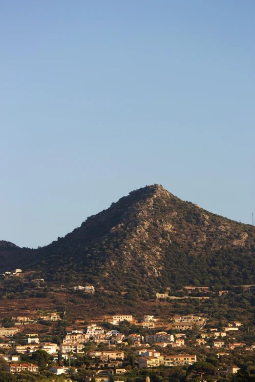 a view of a town with a mountain in the background, traditional corsican, neck zoomed in, sense of scale, colour photograph