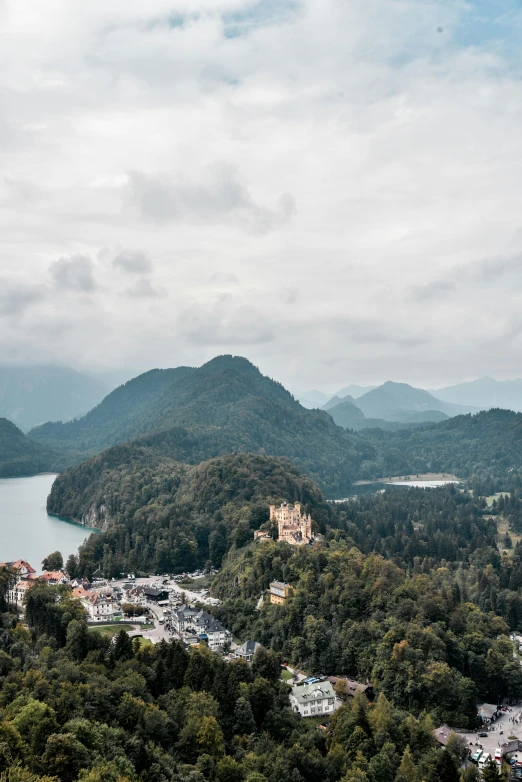 a castle sitting on top of a lush green hillside, by Sebastian Spreng, unsplash contest winner, mountains and lakes, high view, city buildings on top of trees, slightly pixelated