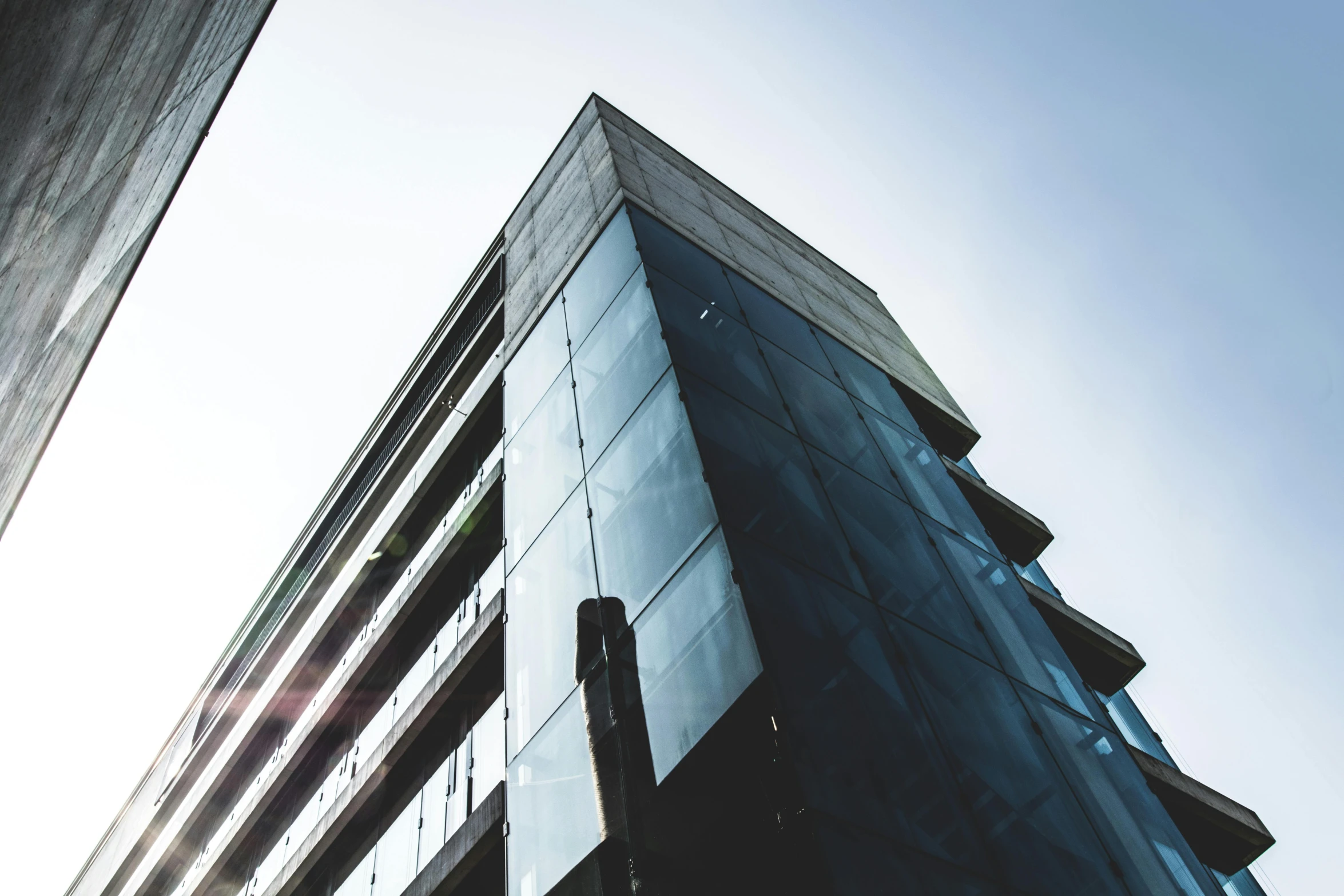 a tall building sitting in the middle of a city, a photo, unsplash, bauhaus, close up shot from the side, espoo, tall obsidian architecture, strong sunlight