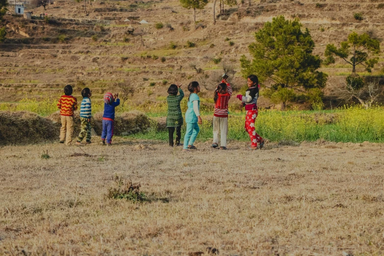 a group of people standing in a field, pexels contest winner, hurufiyya, uttarakhand, kids playing, panoramic, fan favorite