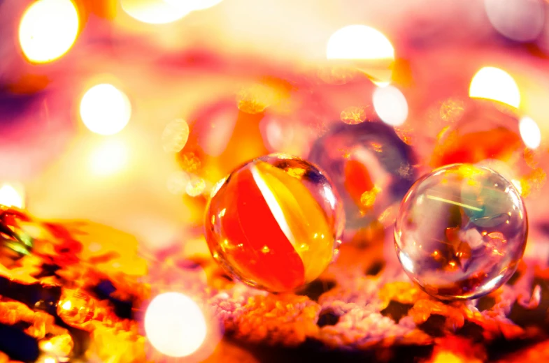 a bunch of marbles sitting on top of a table, a macro photograph, by Julia Pishtar, pexels, orange and red lighting, glittering multiversal ornaments, stylized illustration, red yellow